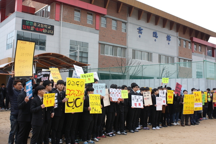 문명고 입학식이 열린 지난 3월2일 오전 경북 경산시 문명고 운동장에 학생과 학부모들이 국정 역사교과서 연구학교 신청 철회를 요구하며 손팻말을 들고 있다. 경산/김일우 기자 cooly@hani.co.kr