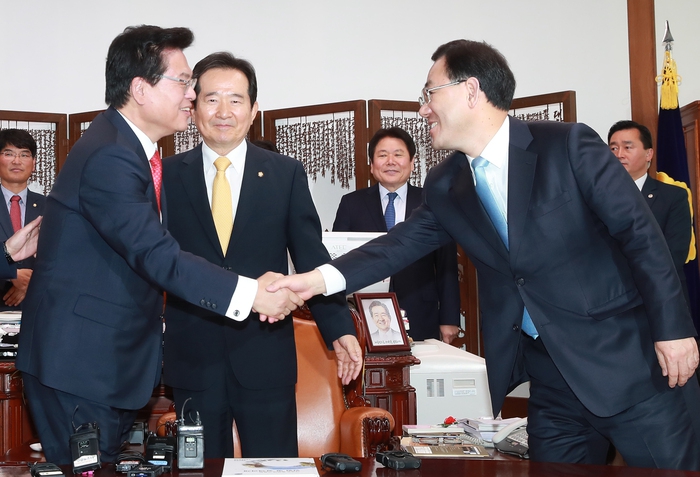 자유한국당 정우택 원내대표(왼쪽)와 바른정당 주호영 원내대표가 15일 오전 서울 여의도 국회의장실에서 열린 19대 대선 뒤 첫 교섭단체 원내대표 회동 때 악수하고 있다. 정세균 국회의장(가운데)이 이들을 바라보고 있다. 연합뉴스