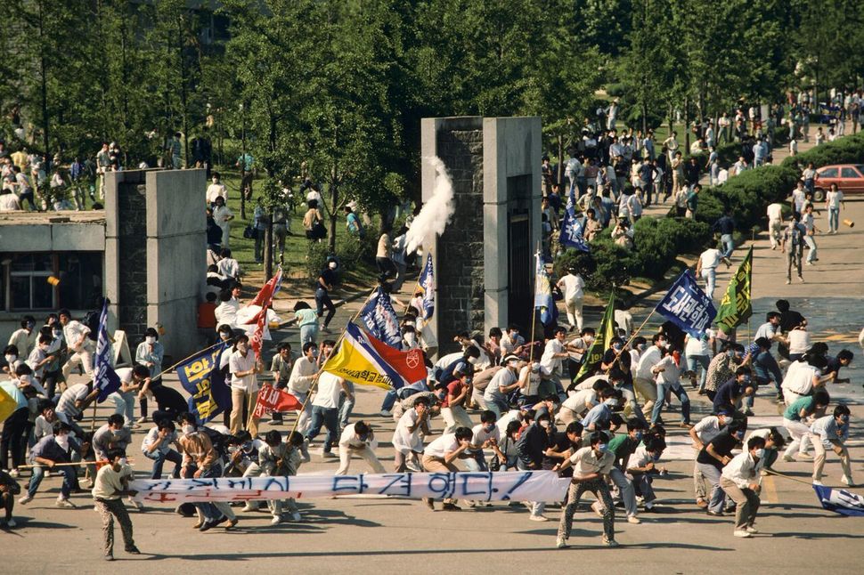 1987년 6월9일 서울 연세대학교 앞에서 이한열 열사가 피격되기 직전의 모습. 왼쪽 흰 현수막 뒤에 영문자로 ‘연세’라고 쓰인 티셔츠를 입고, 푸른색 마스크를 쓰고 있는 이한열 열사의 모습이 보인다. 네이선 벤 제공