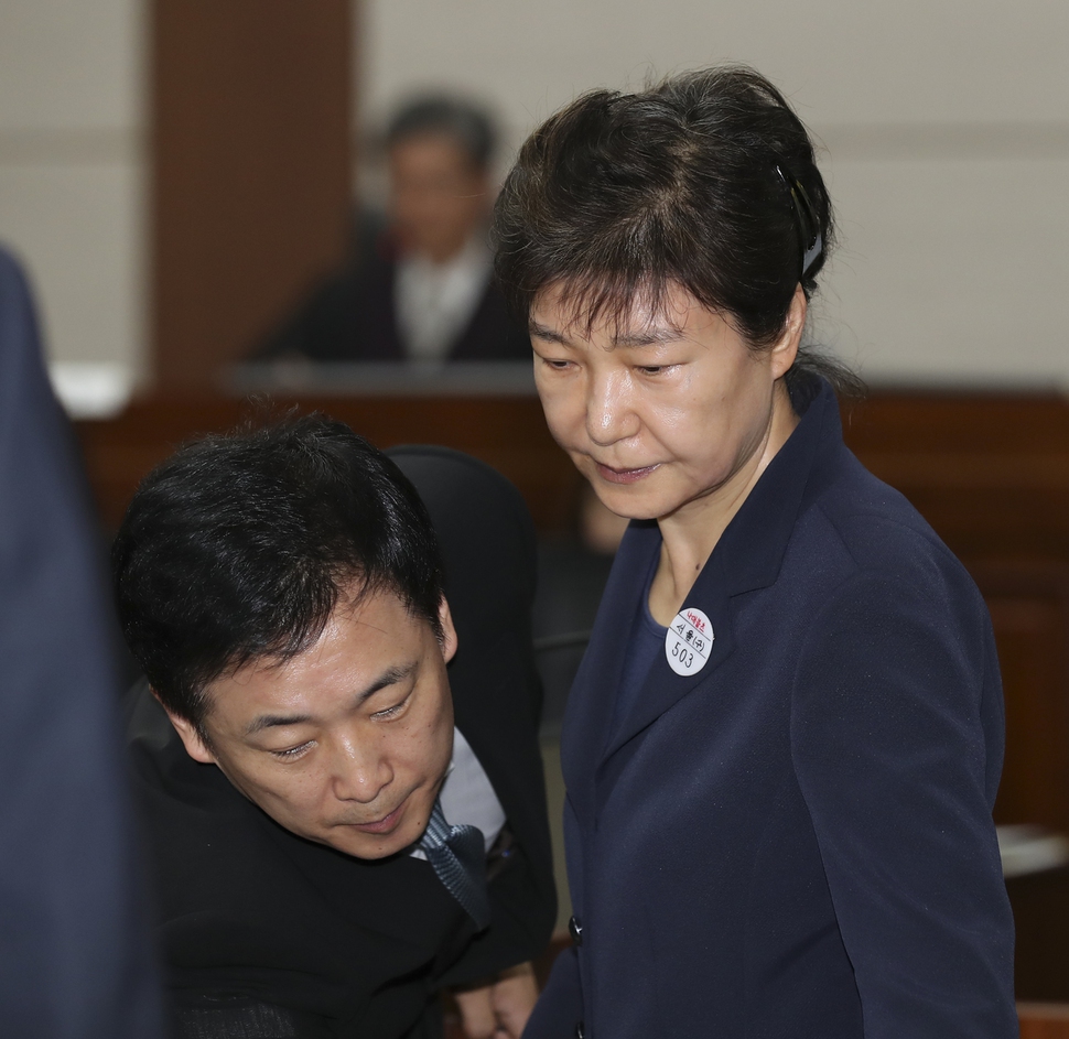 뇌물혐의 등으로 구속 기소된 박근혜 전 대통령이 23일 오전 서울 서초동 서울중앙지방법원417호 형사대법정에서 열린 첫 정식재판에 출석하여 유영하 변호사의 안내를 받고 있다. 이날 재판에는 함께 기소된 최순실씨, 신동빈 롯데그룹 회장이 박 전 대통령과 피고인석에 섰다. 사진공동취재단