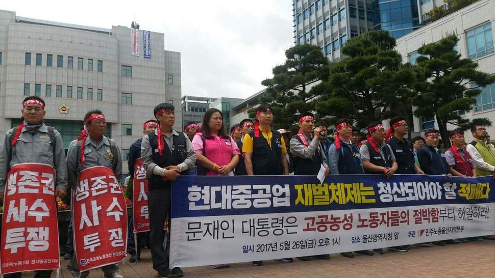 민주노총 울산본부는 26일 울산시청 앞에서 기자회견을 열고 “박근혜 정부의 적폐정책인 조선산업 구조조정을 폐기하고, 현대중공업 사태 해결에 적극 나설 것”을 문재인 정부에 촉구했다. 뒤쪽으로 울산시의회 의사당 옥상에서 농성하는 금속노조 현대중공업지부 간부 2명의 모습이 보인다. 민주노총 울산본부 제공