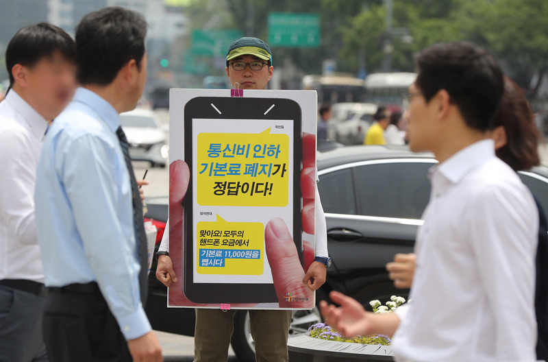 참여연대 관계자가 지난달 31일 오후 서울 종로구 광화문광장에서 이동통신 기본료 폐지를 촉구하는 1인 시위를 하고 있다. 연합뉴스