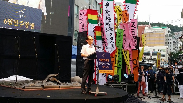 6월 민주항쟁 당시 ‘민주헌법쟁취 국민운동부산본부’의 사무국장을 맡았던 고호석(62)씨가 10일 부산 중구 광복로 시티스폿(옛 미화당백화점) 앞에서 열린 ‘6월 민주항쟁 30년 부산 기념식’에서 경과보고를 하고 있다.