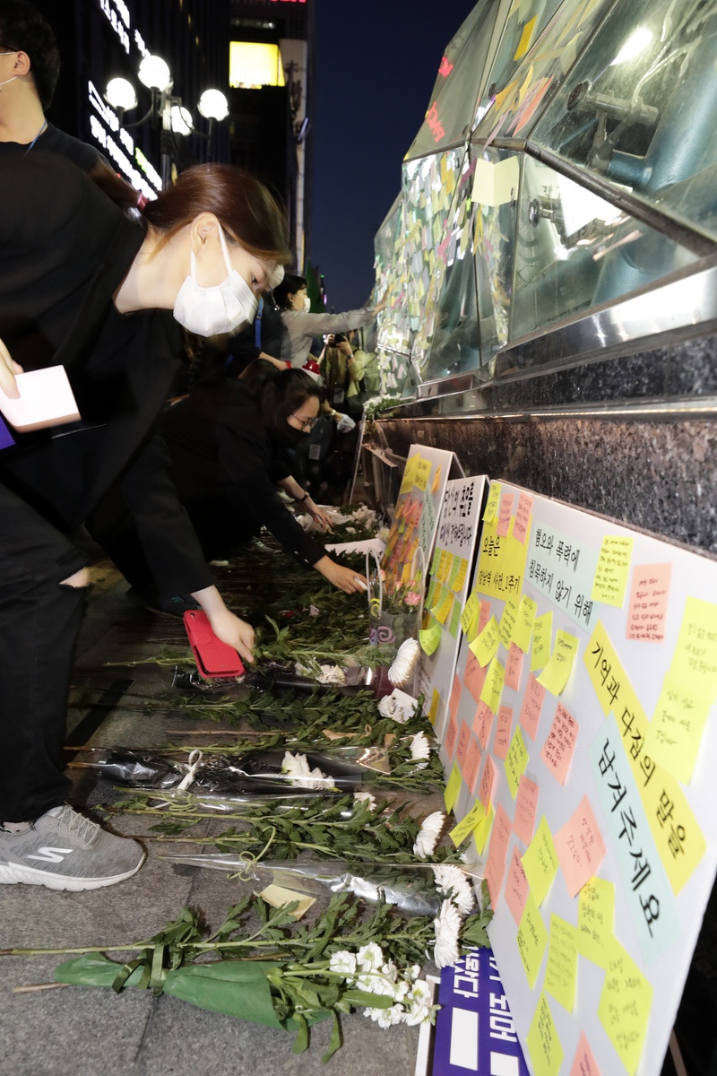 강남역 여성살해사건 1주기 추모행동 행사가 열린 17일 저녁 참가자들이 강남역 10번 출구에서 희생자를 추모하는 의미로 국화를 헌화하고 포스트잇을 붙이고 있다. <한겨레> 자료사진
