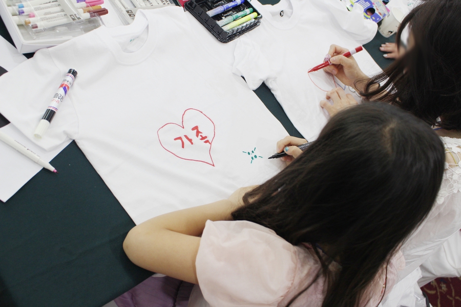 양육비이행관리원이 연 비양육부모와 아이들의 관계 개선 프로그램에 참여한 한 아이가 부모와 함께 입을 흰 티셔츠를 꾸미고 있다. 양육비이행관리원 제공