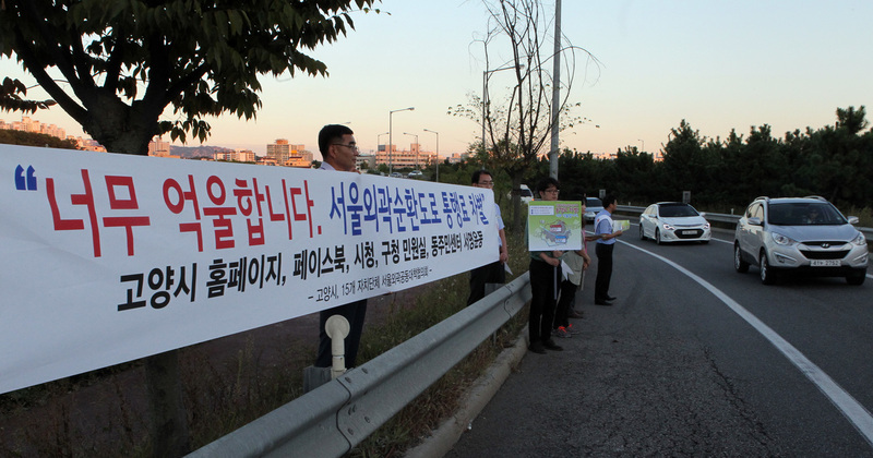 고양시 관계자들이 2015년 9월17일 경기 고양시 서울외곽순환도로 고양나들목에서 “너무 억울합니다. 통행료 차별”이라는 현수막을 들고 통행요금 인하의 당위성을 알리는 캠페인을 벌이고 있다. 고양/연합뉴스