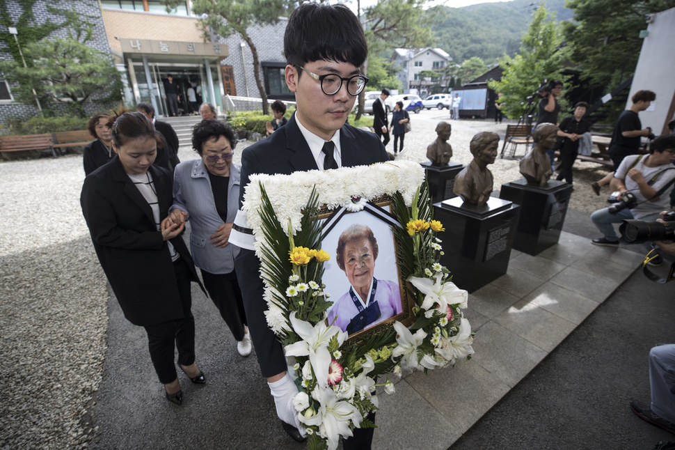 일본군 ‘위안부’ 피해자 김군자 할머니의 노제가 25일 오전 경기도 광주시 나눔의 집에서 열려 상주가 고인의 영정사진을 들고 운구차로 향하고 있다. 고인의 유해는 퇴촌성당에서의 마지막 미사 후 서울 양재동 서울추모공원에서 화장된 뒤 나눔의 집 법당에 안치된다. 광주/김성광 기자 flysg2@hani.co.kr