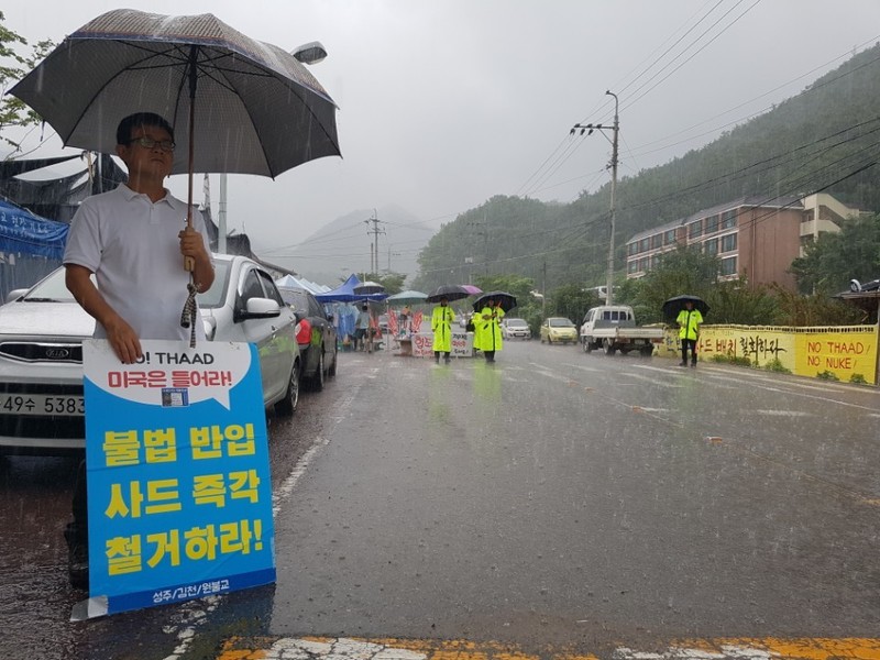 31일 오후 경북 성주군 초전면 소성리 회관 앞 도로에서 성주 주민 박수규(54)씨가 우산을 들고 혼자 성주골프장으로 가는 차량을 감시하고 있다. 김일우 기자