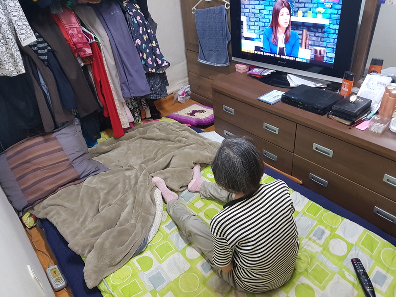 지난달 14일 서울 종로구에 거주하고 있는 치매 독거노인 김지영(가명)씨가 텔레비전 뉴스를 시청하고 있다. 전국 대부분 지역에 폭염 특보가 내려진 이날, 김씨는 집안 모든 환기구를 닫아 놓은 채 겨울용 털이불을 덮고 생활하고 있었다.