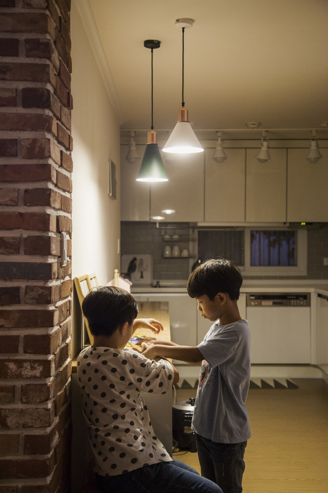 하람, 바음 두 아들이 거실에 놓인 수납장 앞에서 놀이를 하고 있다. 수납장 위 조명이 평화로운 느낌을 준다. 윤동길(스튜디오 어댑터 실장)