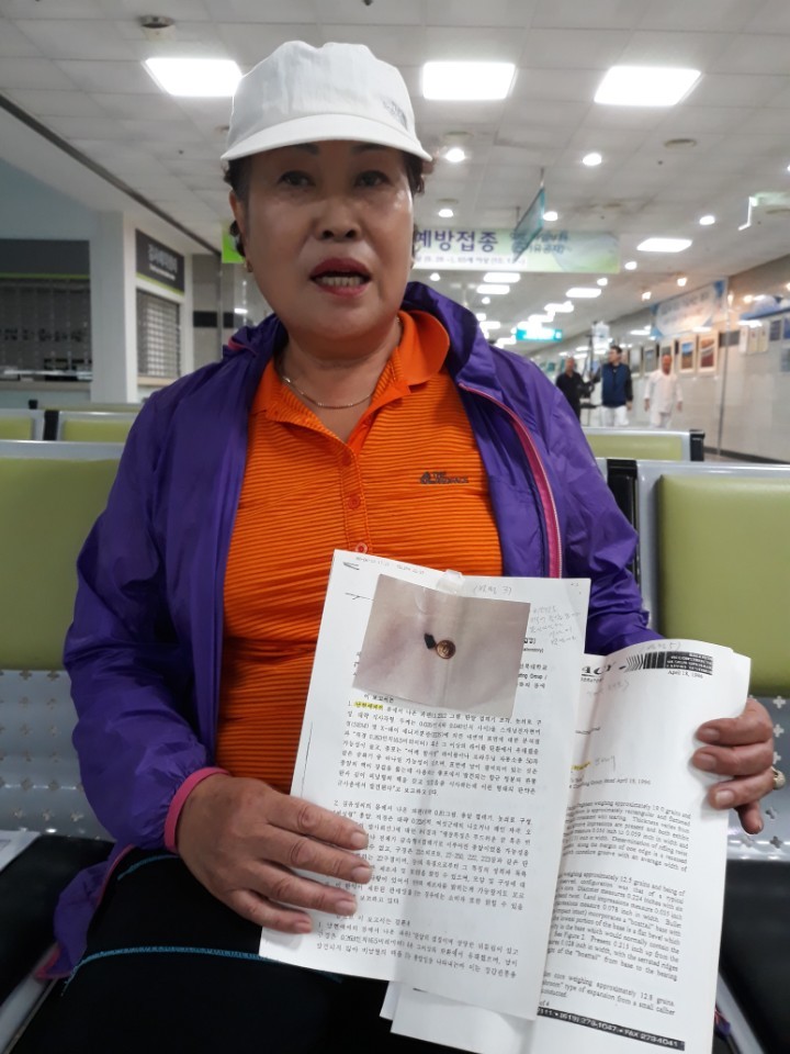 5·18 피해자 남현애씨가 11일 오후 광주보훈병원에서 자신의 몸속에서 나온 탄환이 ‘엠(M)50 브라우닝(Browning) 엠지(Machine Gun)’ 이상의 철합금탄으로 자동기관총의 파편이라는 분석 내용이 담긴 미국 무기실험연구소의 조사결과 보고서 원본을 들어 보이고 있다. 정대하 기자