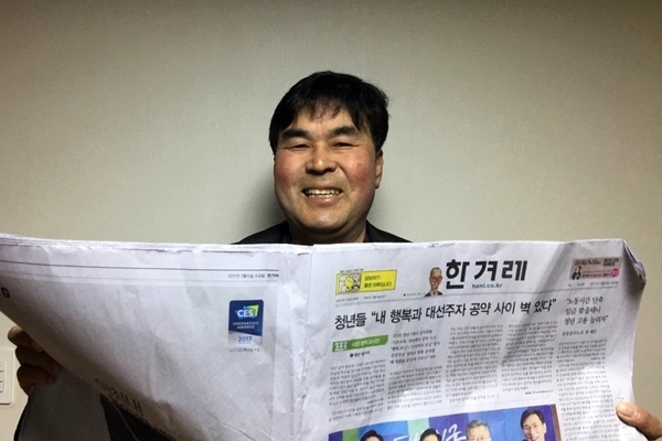 새 주주 곽기종씨가 <한겨레> 신문을 보며 활짝 웃고 있다.   한겨레 자료사진