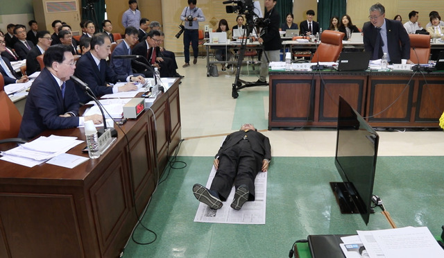 19일 서울 종로구 감사원에서 열린 국회 법제사법위원회 국정감사에서 노회찬 정의당 의원이 신문지를 깔고 바닥에 드러누워 일반 수용자의 과밀 수용 실태를 보여주고 있다. 노회찬 의원실 제공