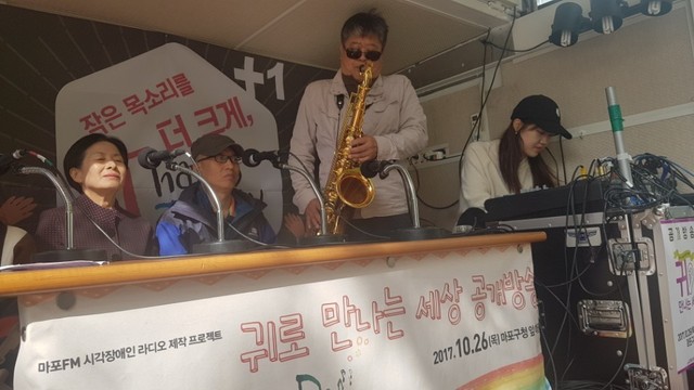 26일 낮 서울 마포구청 앞 공터에서 열린 마포공동체라디오(마포FM) <귀로 만나는 세상> 공개방송에서 시각장애인 김규백(65)씨가 색소폰 연주를 하고 있다.