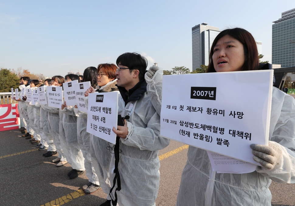 20일 오전 경기 수원시 삼성디지털시티 정문 앞에서 반올림(반도체 노동자의 건강과 인권 지킴이)가  주최한 기자회견에서 참가자들이 삼성전자 반도체 노동자들의 산업재해를 인정하고 즉각 보상하라는 내용의 손팻말을 들어 보이고 있다. 연합뉴스