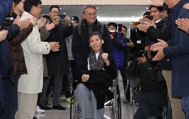 제5회 리영희상을 수상한 이용마 문화방송 해직 기자가 1일 저녁 서울 마포구 공덕동 한겨레신문사에서 열린 시상식에 참석하기 위해 행사장에 들어서고 있다. 동료 언론인들의 박수에 이 기자가 미소를 띤 얼굴로 주먹을 들어 보이고 있다. 뒤에서 휠체어를 끄는 이는 김민식 문화방송 피디. 이정우 선임기자 woo@hani.co.kr