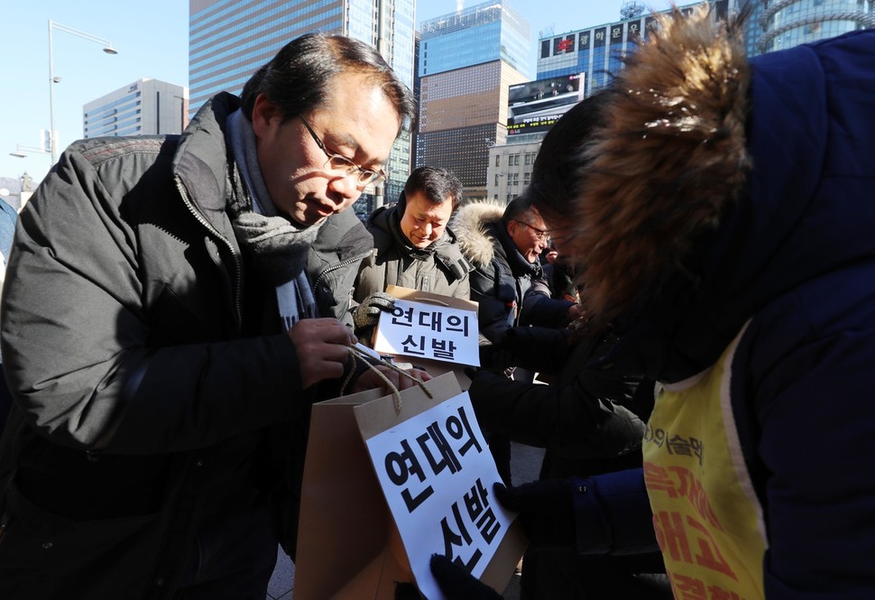 민주노총 관계자 및 시민사회단체 회원들이 27일 오전 서울 중구 동화면세점 앞에서 하이디스 해고노동자들에게 ‘연대의 신발’을 전달하고 있다. 신소영 기자