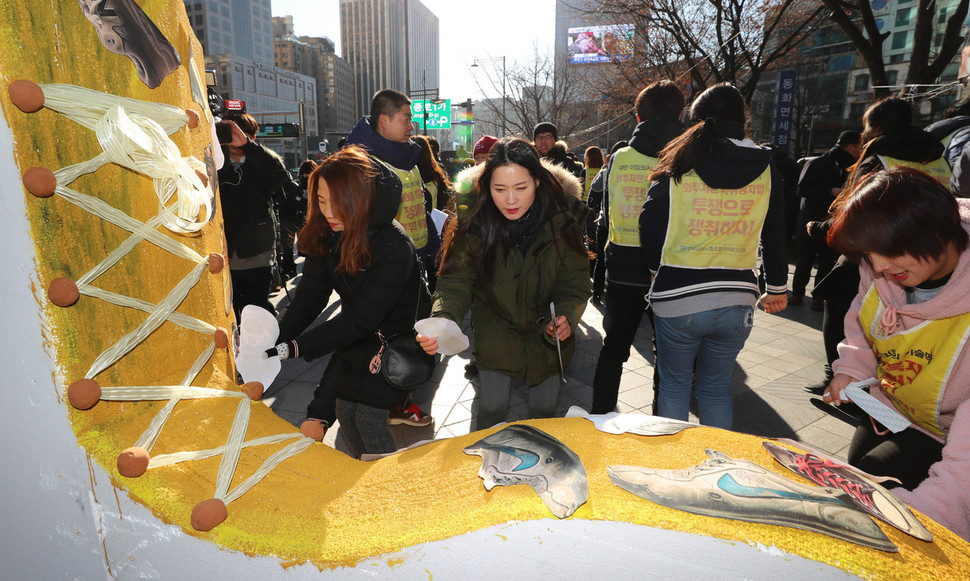 하이디스 해고 노동자들이 27일 오전 서울 중구 동화면세점 앞에서 대형 신발 모형에 신발 사진을 붙이고 있다. 신소영 기자