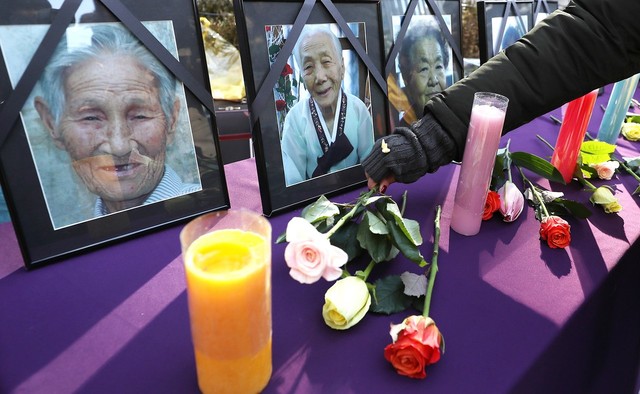 27일 오후 서울 종로구 옛 주한일본대사관 앞에서 정대협 주최로 열린 '일본군 위안부 문제 해결을 위한 정기 수요시위'에서 정대협 관계자들이 올 한해 돌아가신 할머니들의 영정사진 앞에 꽃을 놓고 있다. 연합뉴스