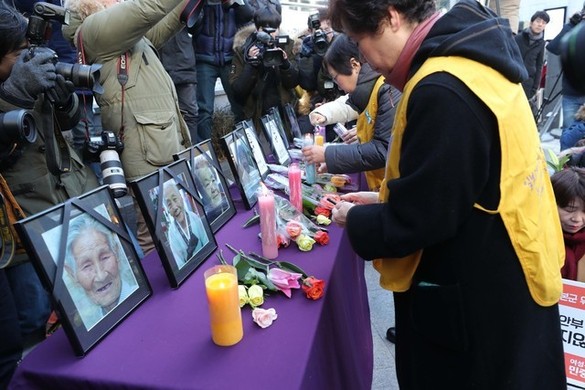 지난 27일 서울 종로구 옛 일본대사관 앞에서 열린 제1315차 일본군 ‘위안부’ 문제 해결을 위한 정기 수요시위 및 위안부 피해자 추모제에서 정대협 관계자들이 올해 세상을 떠난 위안부 피해자 할머니들 영정사진 앞에 꽃을 놓고 있다. 백소아 기자 thanks@hani.co.kr