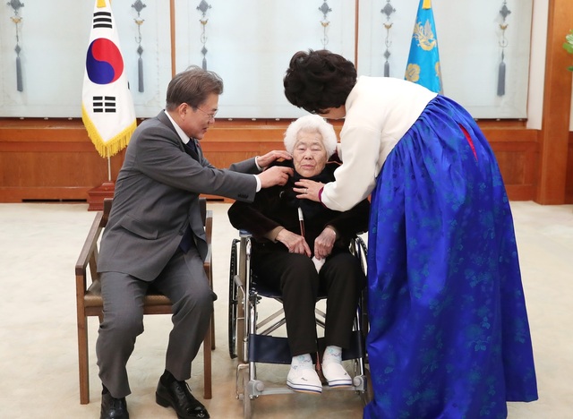 문재인 대통령과 부인 김정숙 여사가 4일 오후 일본군 위안부 피해 할머니 초청 오찬에 참석한 이옥선 할머니의 옷맵시를 기념촬영을 하기 전 만져주고 있다. 청와대 제공