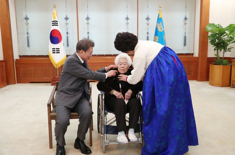 문재인 대통령과 김정숙 여사가 4일 일본군 ‘위안부’ 피해자 초청 오찬에 참석한 이옥선 할머니와 기념촬영을 준비하며 이 할머니의 옷맵시를 고쳐주고 있다. 청와대 제공