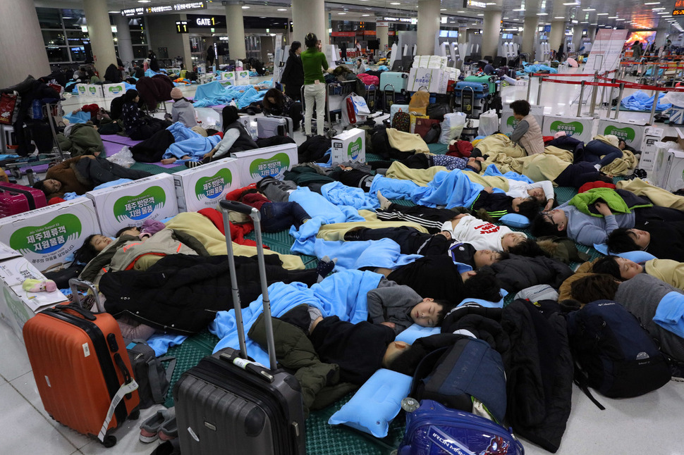 12일 오전 제주공항 3층 출발대합실에서 전날 내린 눈 때문에 비행기를 못탄 어린이 등이 바닥 매트를 깔고 잠을 자고 있다. 연합뉴스