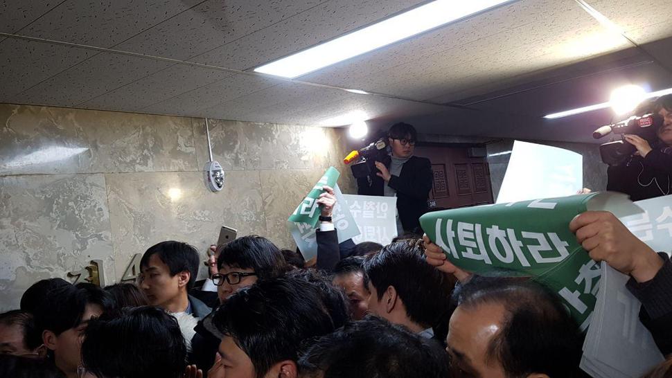 12일 국민의당 당무위가 열린 국회 본청 246호실 앞에서 통합 반대파들이 “안철수는 사퇴하라”는 인쇄물을 들어 보이며 항의하고 있다. 송경화 기자