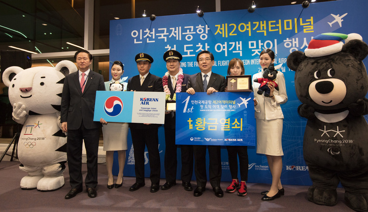 18일 새벽 인천국제공항 제2여객터미널에서 열린 ‘첫 고객 맞이’ 행사에서 우기홍 대한항공 부사장(맨왼쪽), 최운식 대한항공 기장(왼쪽 네번째), 정일영 인천공항공사 사장(다섯번째), 첫 손님 정유정(여섯번째)씨가 기념 촬영을 했다. 사진 대한항공 제공