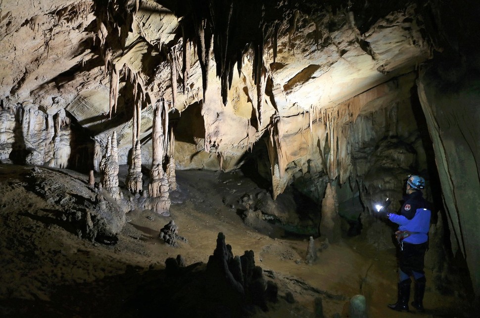 백룡동굴 안에서 안내자가 크고 작은 종유석과 석순 등에 조명등을 비추고 있다.