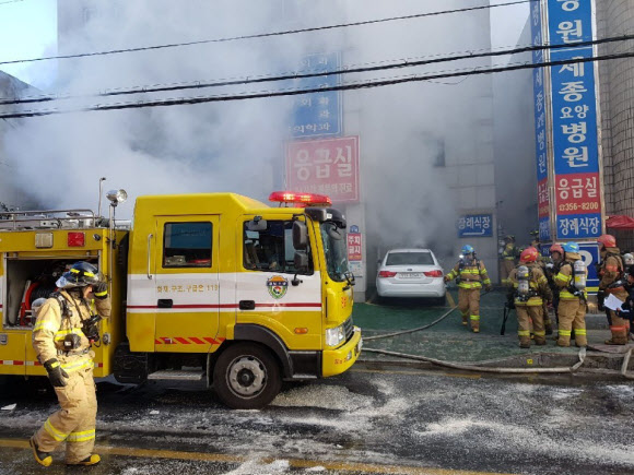 26일 오전 경남 밀양시 가곡동 세종병원에서 불이나 소방관들이 화재 진압 작업을 벌이는 동안 연기가 뿜어져 나오고 있다. 현재까지 사망자가 8명으로 늘어난 것으로 알려졌다. 밀양/연합뉴스