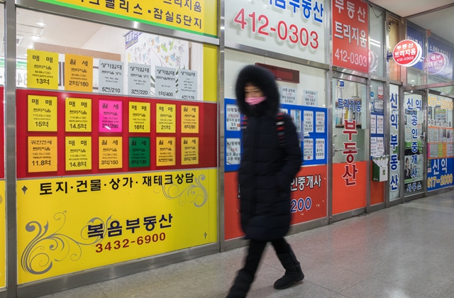 올해 시행되는 재건축초과이익환수제는 서울 재건축 아파트의 투기 수요를 잠재울 수 있을까. 1월24일 서울 잠실의 한 아파트 상가 내 부동산중개소 앞을 주민이 지나가고 있다.