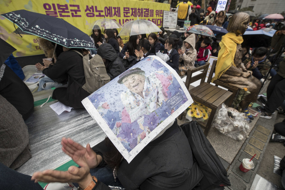 삼일절을 하루 앞둔 28일 낮 서울 종로구 옛 일본대사관 앞에서 ‘제1324차 일본군성노예제 문제해결을 위한 정기 수요시위’가 열려, 우산을 쓰고 소식지 등으로 머리를 가린 참석자들이 비를 맞으며 일본 정부의 사과를 요구하고 있다. 김성광 기자 flysg2@hani.co.kr