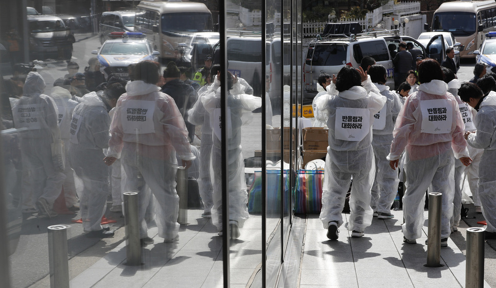 삼성공장 반도체 공장에서 일하다 백혈병으로 숨지면서 반도체 공정의 직업병 논란을 세상에 처음 알린 고황유미 씨의 11주기인 6일 오후 고 황유미 씨와 삼성 산재사망 노동자 추모의 날 행진에 참가한 이들이 서울 용산구 한남동 리움미술관 유리벽 옆에서 반도체 공장의 상징하는 방진복으로 갈아입으며 행진을 준비하고 있다. 이정아 기자