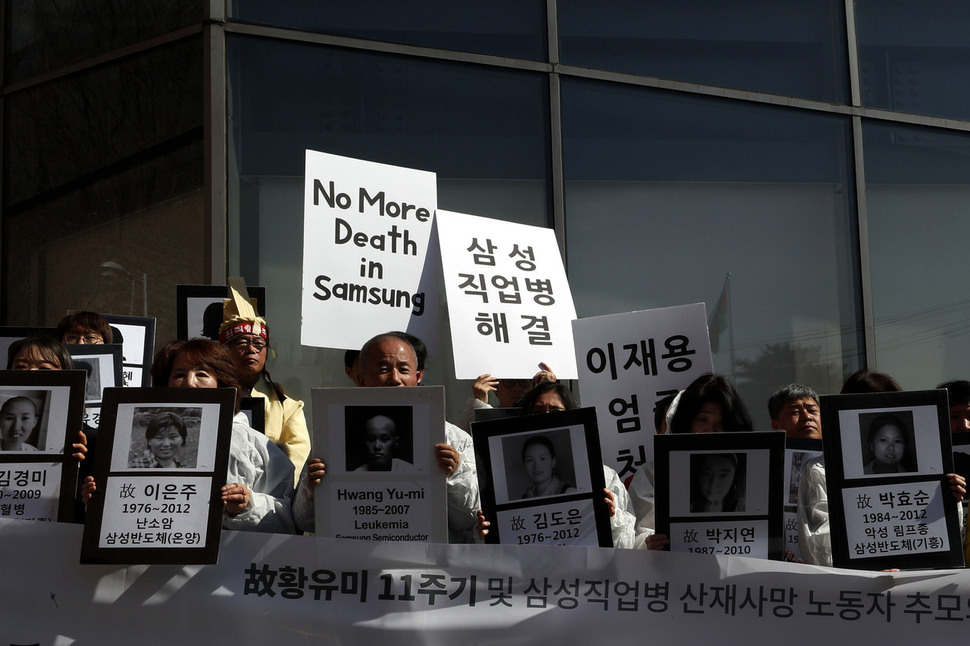 황상기 씨(앞줄 왼쪽 셋째)를 비롯한 참가자들이 희생자들의 출생·사망년도와 병명이 쓰인 영정을 들고 있다. 이정아 기자