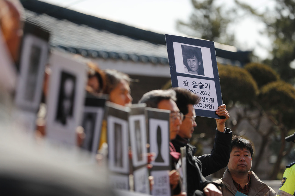 참가자들이 희생자들의 출생·사망년도와 병명이 쓰인 영정을 들고 있다. 이정아 기자