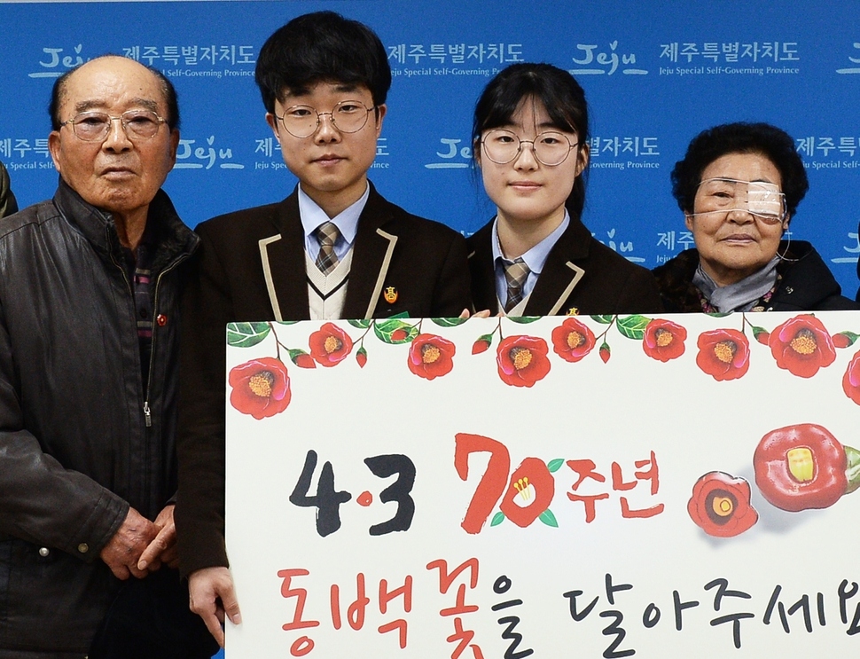 제주 애월고 학생들이 4·3 후유장애를 앓고 있는 고태명씨(왼쪽)와 윤옥화(오른쪽)씨에게 동백꽃 배지를 전달하고 기념사진을 찍고 있다. 허호준 기자