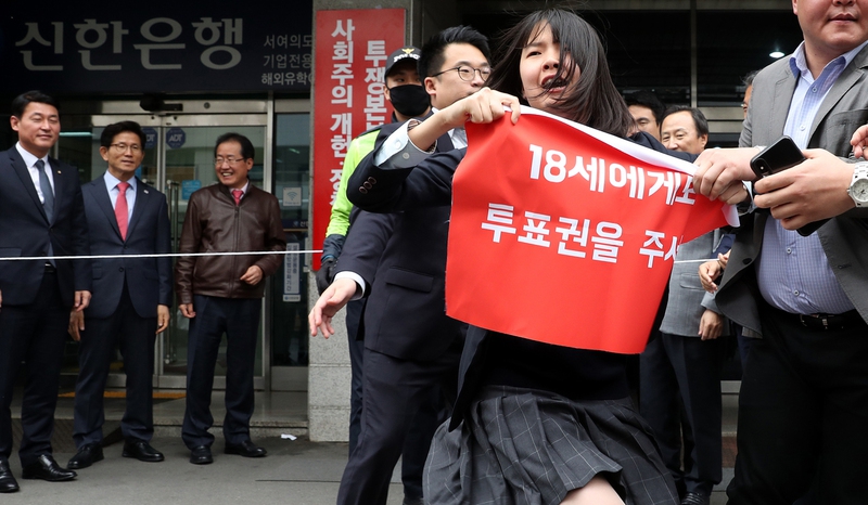 홍준표 자유한국당 대표(왼쪽 셋째)와 김문수 서울시장 예비후보(왼쪽 둘째) 등 당 지도부가 10일 오후 서울 여의도 당사 들머리에서 ‘사회주의 개헌·정책 저지투쟁본부’ 현판식을 하던 중, 청소년단체 회원들이 선거연령 인하를 요구하는 기습시위를 벌이려다 당직자들의 제지를 받는 모습을 지켜보고 있다. 연합뉴스