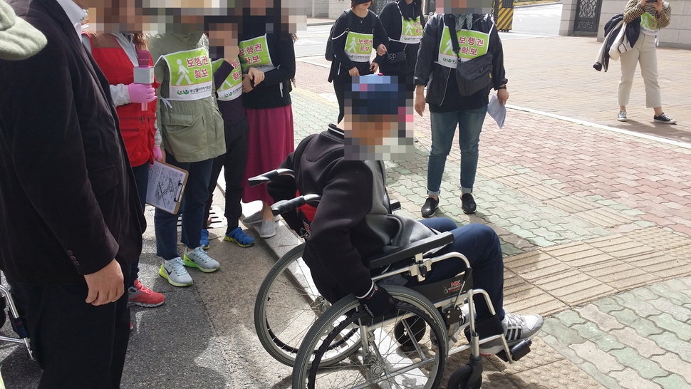 지난 15일 부산 연제구 거제동의 부산 검찰청 앞 횡단보도에서 장애인 보행 체험행사에 참여한 한 청소년이 휠체어를 밀어 인도로 올라가려고 하고 있다. 인도 턱이 높아 애쓰고 있다.