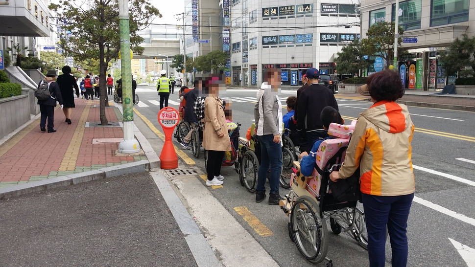 지난 15일 부산 연제구 거제동의 부산지방법원과 부산지방검찰청 앞 인도에서 장애인 보행 체험행사에 참여한 시민들이 높은 턱 때문에 인도에 들어가지 못하고 차도로 휠체어를 밀고 있다.