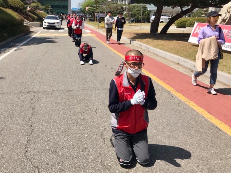 동국대 청소노동자들이 지난 12일 낮 ‘학교는 청소노동자 직접고용 약속을 이행하라’는 기자회견을 한 뒤 동국대 본관 앞 팔정도 주변을 삼보일배로 돌고 있다. 민주노총 제공