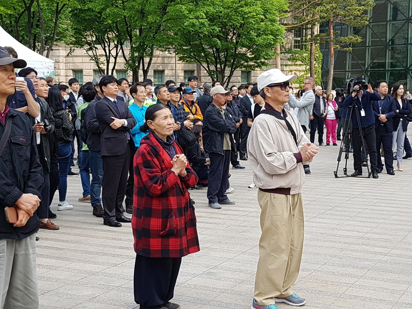 남북 두 정상이 손을 맞잡자 두 시민이 두손을 모으고 생중계를 보고 있다.