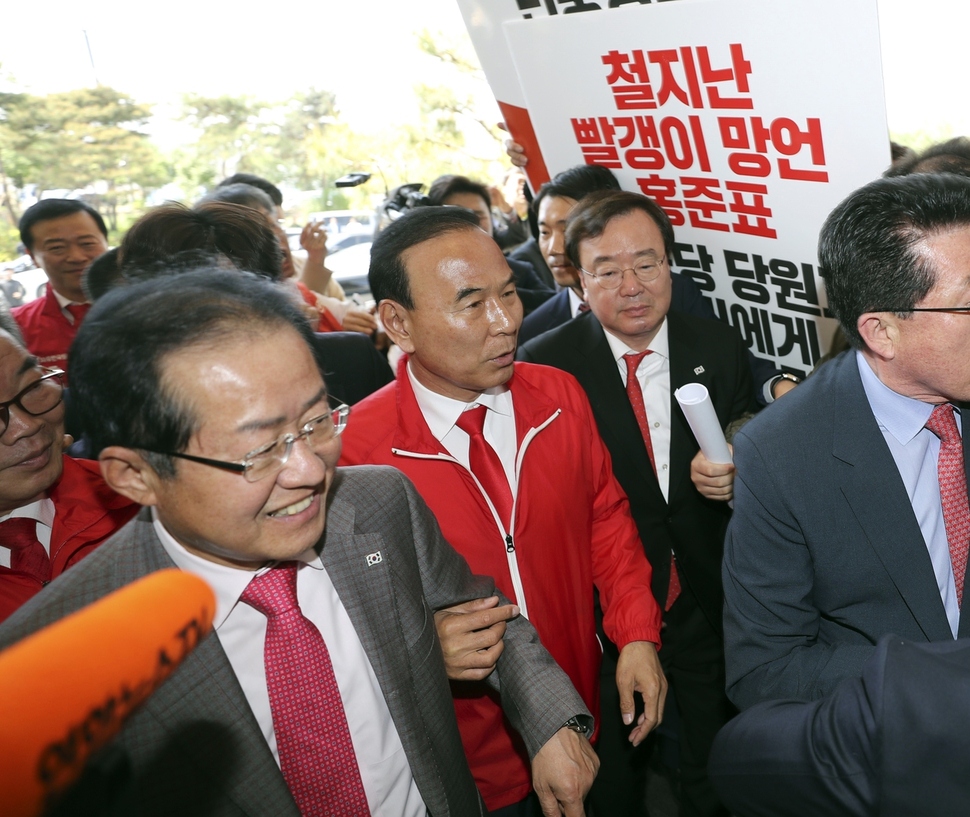 홍준표 자유한국당 대표가 4일 오전 청주에서 열린 ‘지방선거 충북 필승결의대회장’으로 들어서다, 최근 자신의 ‘빨갱이’ 발언을 사과하라는 민중당 당원들을 보며 웃고 있다. 청주/연합뉴스