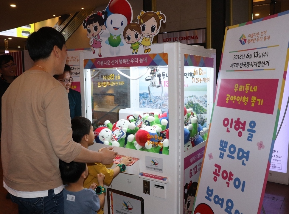 지난 2일 전주 롯데백화점에 설치된 공약인형 뽑기 기계에서 한 유권자가 아이와 함께 기계를 조작하고 있다. 전북선관위 제공