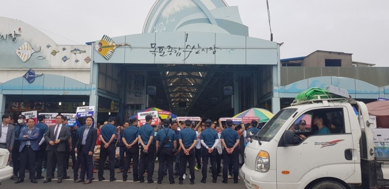 더불어민주당 중앙선대위원들이 전남 목포종합수산시장 유세에 나서기로 한 8일, 민주당 지도부가 도착하기 전 민주노총 전남본부 조합원들이 ‘최저임금 삭감법 폐기하라’ 등이 적힌 손팻말을 들고 시위를 펼치고 있다.