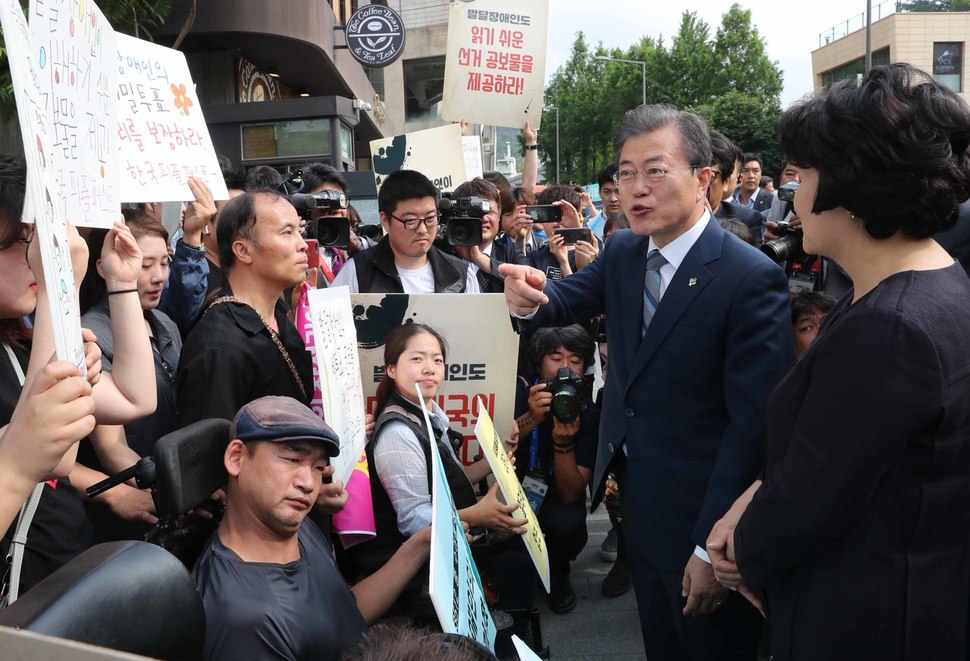 문재인 대통령이 8일 오전 서울 종로구 삼청동 주민센터를 찾아 6·13 지방선거 사전투표를 한 뒤 나오다 장애인들의 참정권을 요구하는 시민단체 회원들을 만나 얘기를 나누고 있다. 연합뉴스.