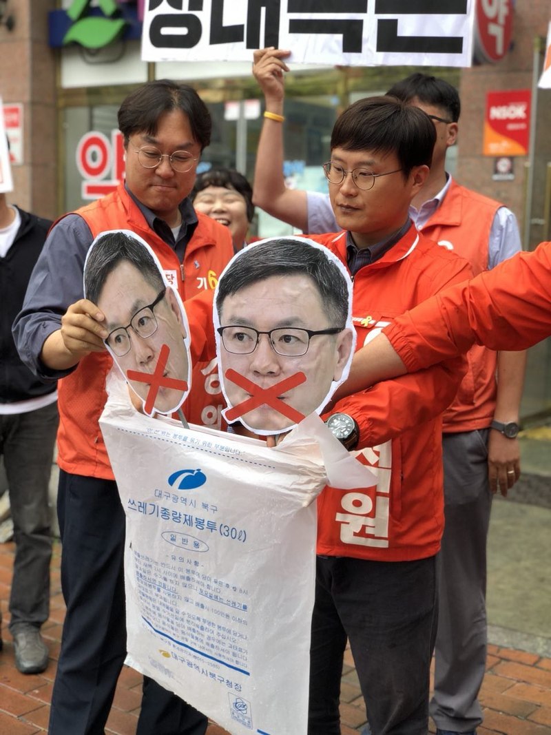 11일 오전 민중당 대구시당 당원들과 민중당 후보들이 대구 북구 산격동 정태옥 의원 지역 사무소 앞에서 종량제 쓰레게 봉투에 정 의원의 얼굴 모형을 담는 행위극을 하고 있다. 민중당 대구시당 제공