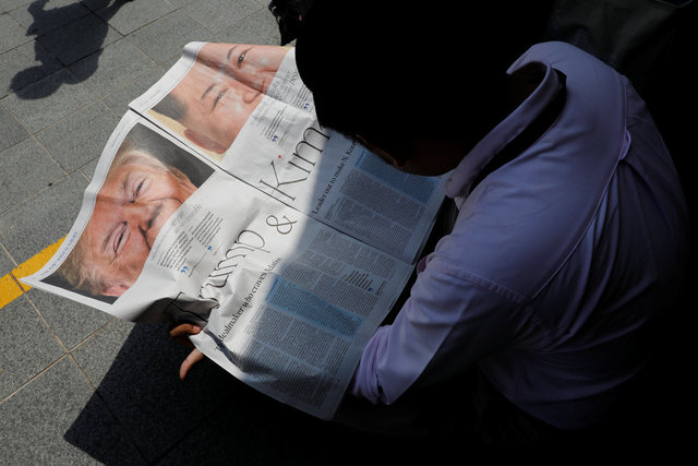 북-미 정상회담을 하루 앞둔 11일 김정은 북한 국무위원장이 머물고 있는 싱가포르 세인트 리지스 호텔 인근 거리에서 한 기자가 현지 신문에 실린 도널드 트럼프 미국 대통령과 김 위원장 관련 특집 기사를 읽고 있다. 싱가포르/로이터 연합뉴스