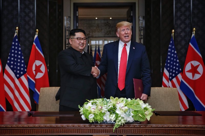 김정은 북한 국무위원장과 도널드 트럼프 미국 대통령이 12일 싱가포르에서 정상회담 공동선언에 서명하고 악수하고 있다. <스트레이츠 타임스> 제공