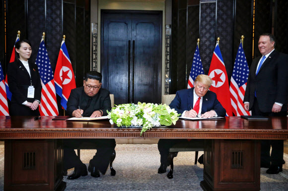 역사적 첫 북미정상회담이 열린 12일 오후 싱가포르 센토사 섬 카펠라호텔에서 북한 김정은 국무위원장과 미국 도널드 트럼프 대통령이 공동합의문에 서명하고 있다. 왼쪽은 김여정 당 제1부부장, 오른쪽은 마이크 폼페이오 국무장관. 연합뉴스